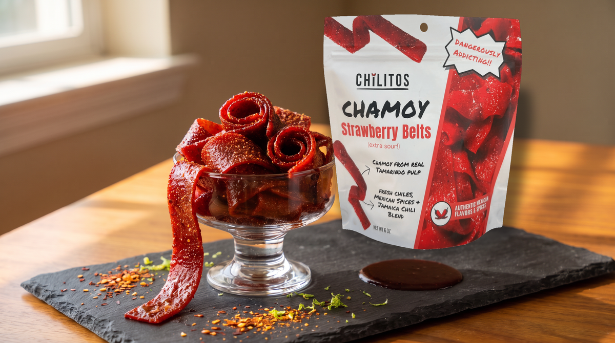 Chilitos strawberry sour belts coated in chamoy and chili in a glass bowl with the Chilitos bag behind on a slate board